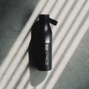 Black Head Space Studios water bottle on a concrete floor with dramatic studio light.